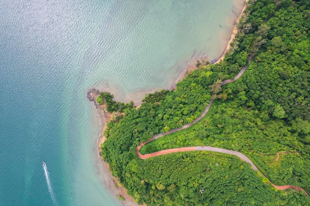 Bovenaanzicht van landelijke weg die door het groene bos en de bergen en het strand loopt