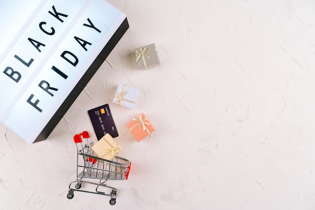 Bovenaanzicht van laptop, zwarte vrijdag promotie verkoop woorden op lightbox, geschenkdozen en trolley. Plat leggen