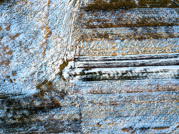 Bovenaanzicht van lege besneeuwde en donkere velden patched landschap op zonnige winterdag. Luchtfoto drone fotografie concept.