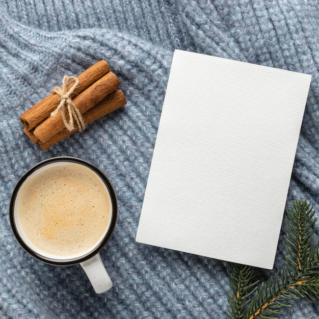 Bovenaanzicht van lege kaart op trui met kopje koffie en kaneelstokjes