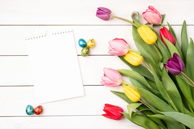 Bovenaanzicht van lege kalender met kleurrijke tulpen op witte achtergrond.