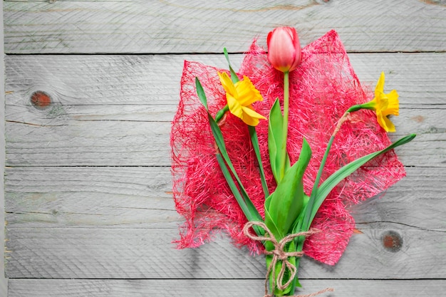 Bovenaanzicht van lente bloemen boeket. Gele narcissen en roze tulp op houten tafel. Kopieer ruimte.