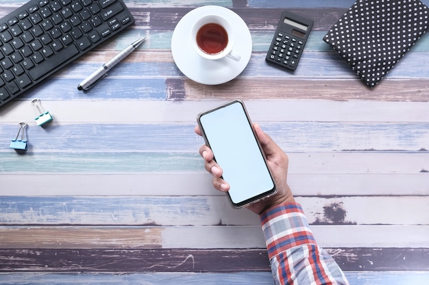 Bovenaanzicht van man hand met slimme telefoon met leeg scherm op Bureau