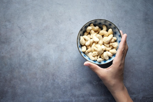 Bovenaanzicht van mannen met een kom cashewnoten op zwarte achtergrond