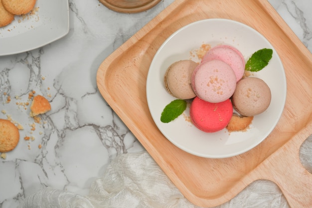 Bovenaanzicht van marmeren eettafel met een plaat van Franse kleurrijke macarons en koekjesplaat