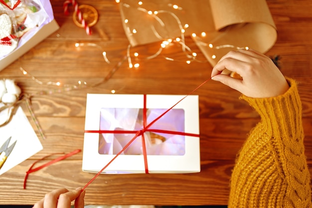 Bovenaanzicht van meisjes handen in oranje gebreide trui opening geschenkdoos nieuwjaar feestelijke sfeer chri...