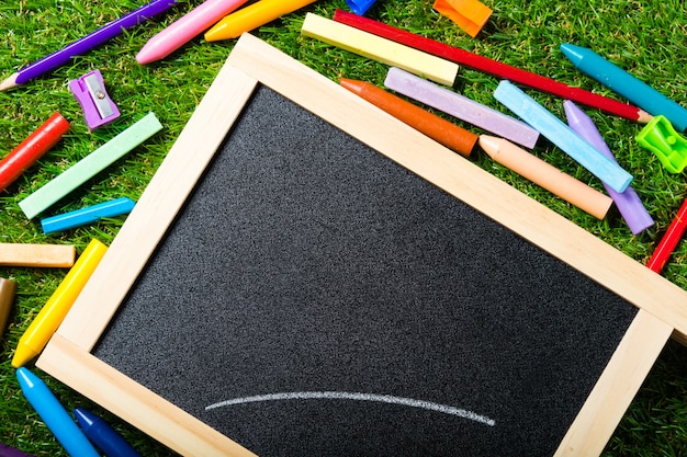 Bovenaanzicht van mini schoolbord en kleuren op plastic gras