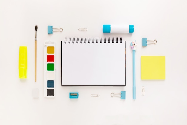 Bovenaanzicht van modern wit, blauw, geel kantoorbureaublad met schoolbenodigdheden en briefpapier op tafel rond lege ruimte voor tekst. Terug naar school concept plat lag met mockup