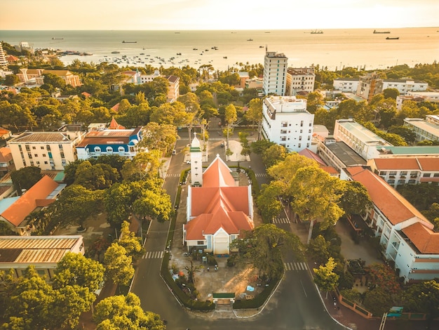 Bovenaanzicht van mooie oude kerk van vung tau stad met groene boom katholieke tempel dorp vung tau vietnam foto van lente landschap met zonsondergang