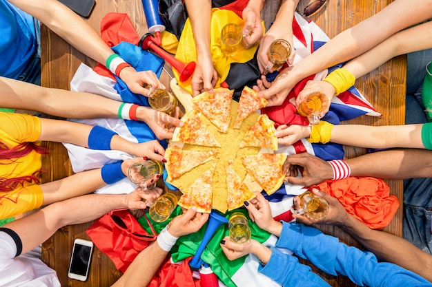 Bovenaanzicht van multi-etnische handen van voetbalsport supporter pizza margherita delen