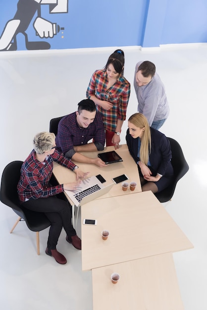 Bovenaanzicht van multi-etnische startende zakenmensengroep op brainstormvergadering in modern, licht kantoorinterieur