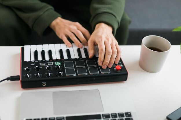 Foto bovenaanzicht van muziekproducent of arrangeur die laptop en midi-keyboard en andere audioapparatuur gebruikt om c