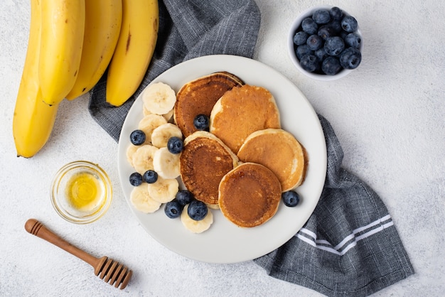 Bovenaanzicht van ontbijtpannekoeken op plaat met honing en bananen
