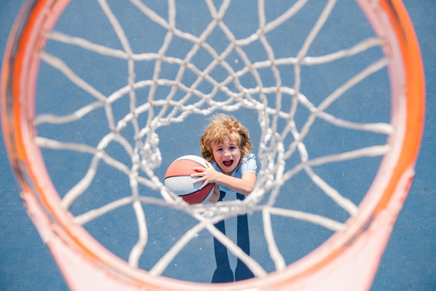 Bovenaanzicht van opgewonden kind dat basketbal speelt met een bal met een blij gezicht.