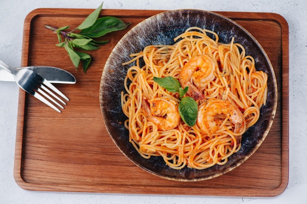 Bovenaanzicht van oranje pasta met garnalen en saus in een bord op een tafel