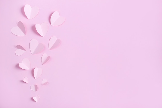 bovenaanzicht van papieren hartjes op roze
