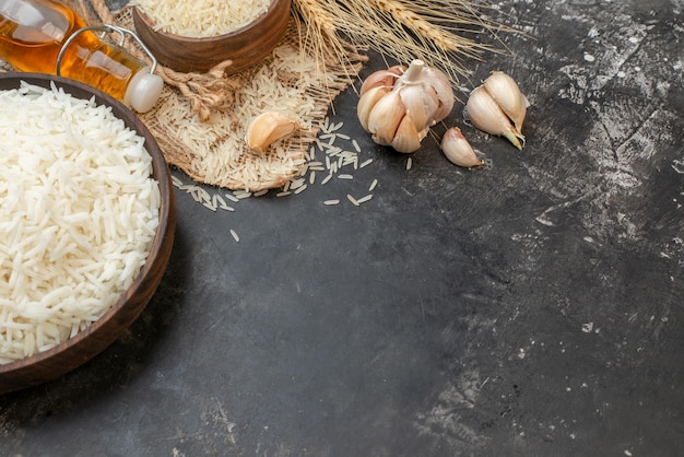 Bovenaanzicht van perfecte lange rijstbruine kommen op naakte kleur handdoek gevallen oliefles knoflook op donkere achtergrond