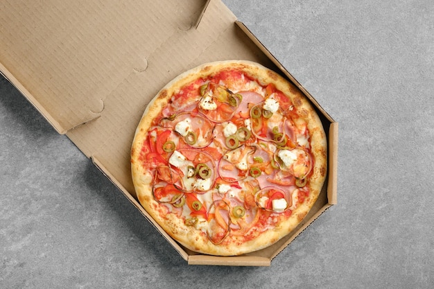 Bovenaanzicht van pizza met ham-ui-olijven en fetakaas in kartonnen doos