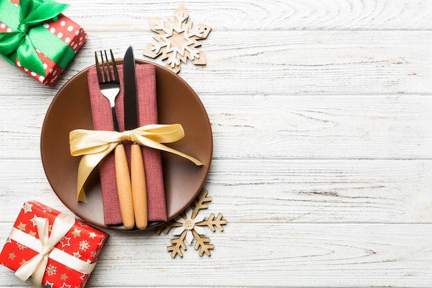 Bovenaanzicht van plaat, vork en mes geserveerd op kerst versierde houten oppervlak