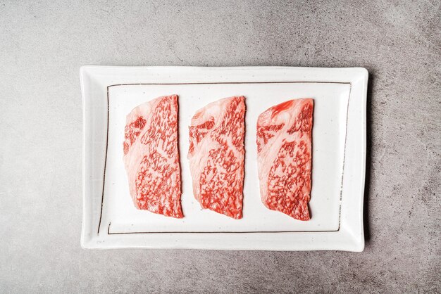 Bovenaanzicht van premium zeldzame plakjes entrecote wagyu a5-rundvlees met hoogmarmertextuur op een keramische plaat