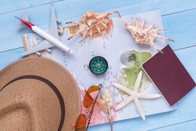 bovenaanzicht van reisaccessoires op lichtblauwe houten plankenvloer voor zomervakantie