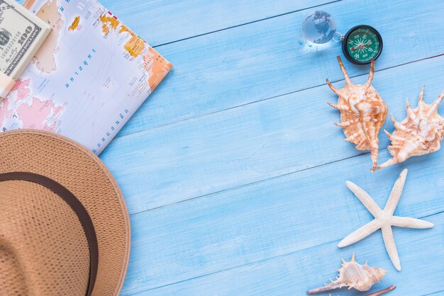 bovenaanzicht van reisaccessoires op lichtblauwe houten plankenvloer voor zomervakantie