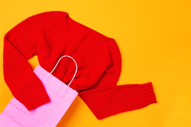 Bovenaanzicht van roze boodschappentas met rode trui. concept van mode en design, winkelen