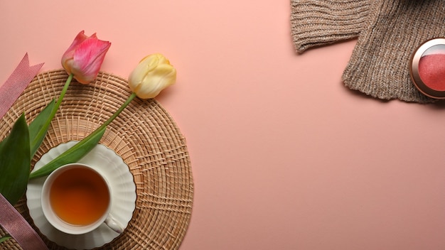 Bovenaanzicht van roze tafel met tae cup, bloemen, trui en kopie ruimte in de woonkamer