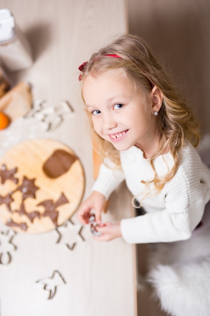 Bovenaanzicht van schattig klein meisje dat kerstkoekjes of peperkoeken maakt in de keuken