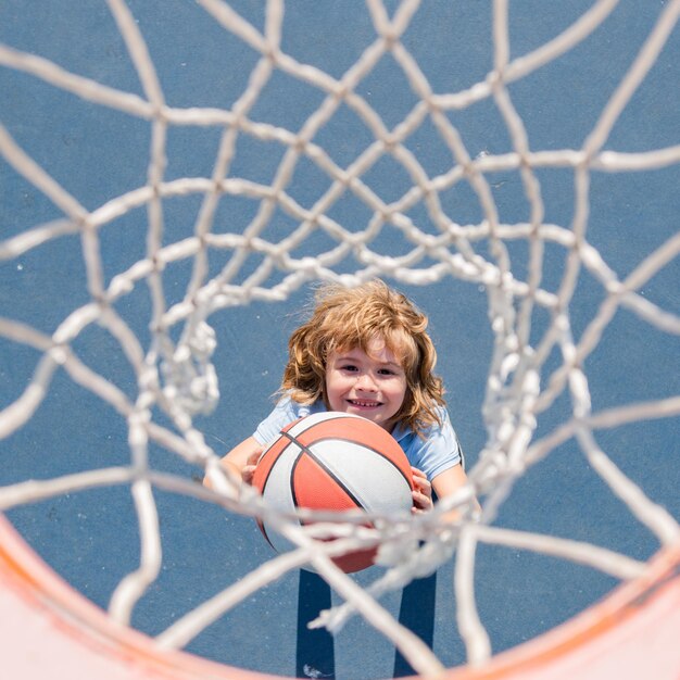 Bovenaanzicht van schattige kindjongen speelt basketbal. Actieve kinderen genieten van buitenspel met basketbalbal.