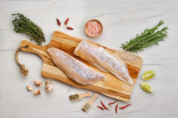 Bovenaanzicht van schelvisfilet met kruiden op houten snijplank