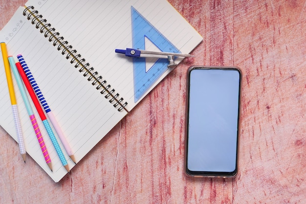 Bovenaanzicht van schoolleveranciers en slimme telefoon op tafel met kopie ruimte.