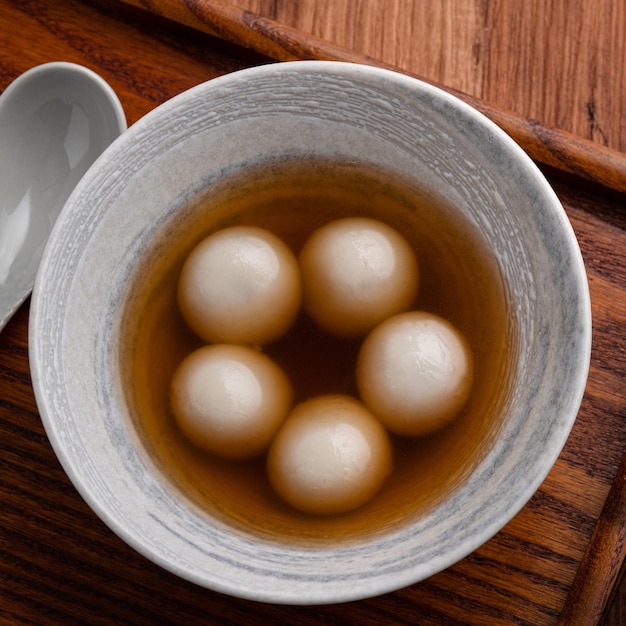 Bovenaanzicht van sesam grote tangyuan (tang yuan, kleverige rijst knoedel ballen) met zoete siroop soep in een kom op houten tafel achtergrond voor winterzonnewende festival voedsel.