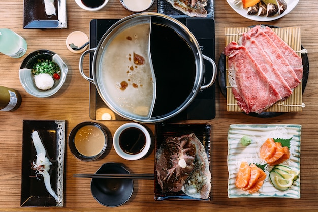 Foto bovenaanzicht van shabu-set, inclusief zeldzame plakken wagyu a5-rund, shabu shoyu en heldere basis.