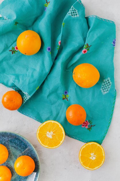 Bovenaanzicht van sinaasappelen met witte achtergrond en vintage turquoise tafelkleed met rustieke plaat
