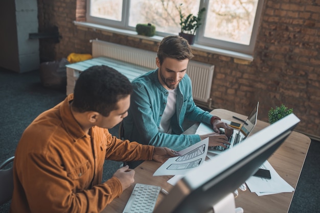 Bovenaanzicht van slimme jonge mannen die een discussie hebben terwijl ze in team werken.