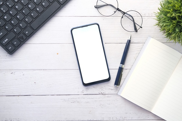 Foto bovenaanzicht van slimme telefoon en kladblok op witte achtergrond