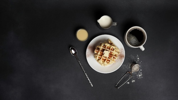 Bovenaanzicht van smakelijke Belgische wafels witte plaat op een zwarte betonnen achtergrond