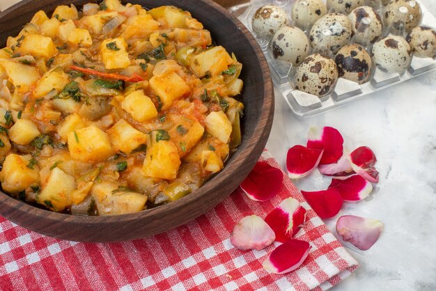 Bovenaanzicht van smakelijke maaltijd met aardappelen op rode gestripte handdoek rozenblaadjes eieren op witte achtergrond