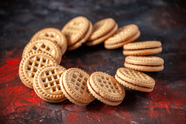 Bovenaanzicht van smakelijke suikerkoekjes gerangschikt in een ronde vorm op mixkleurenachtergrond met vrije ruimte