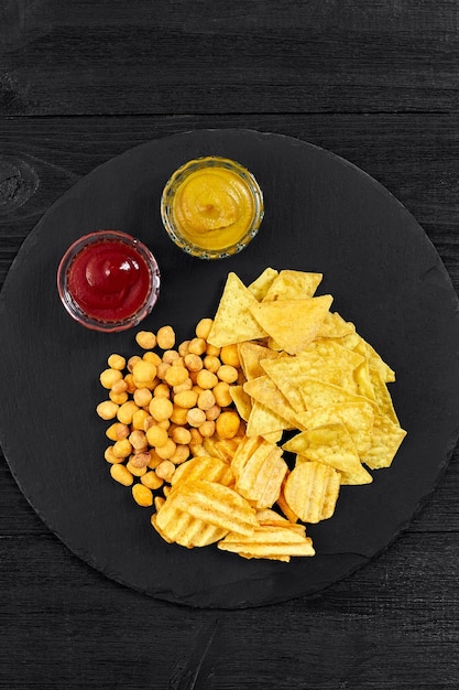 Bovenaanzicht van snacks met saus op zwarte houten tafel