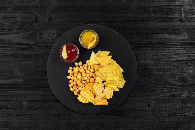 Bovenaanzicht van snacks met saus op zwarte houten tafel