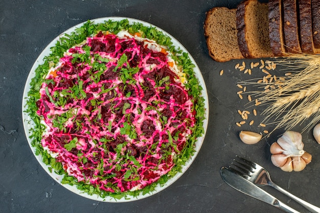 Bovenaanzicht van sneetjes brood spikes bestekset knoflook bestekset en heerlijke salade op donkere kleur achtergrond