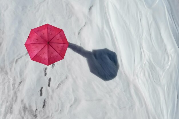 Bovenaanzicht van sneeuwveld met ketting van voetafdrukken die leidt naar de mens verborgen onder werpende lange schaduw