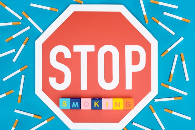 Bovenaanzicht van stopbord sigaretten en blokken met letters geïsoleerd op blauw stop met roken concept