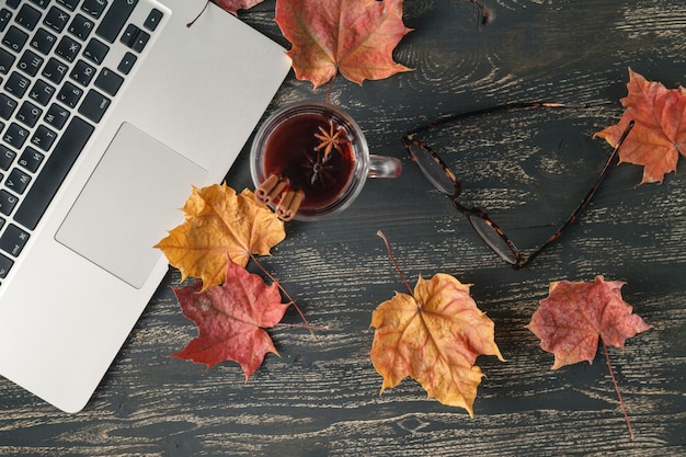 Foto bovenaanzicht van tafel met laptop, drankje en bladeren