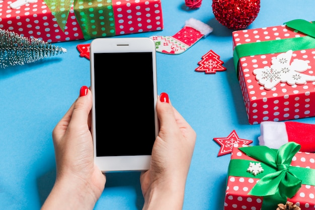 Bovenaanzicht van telefoon in vrouwelijke hand op feestelijke blauw