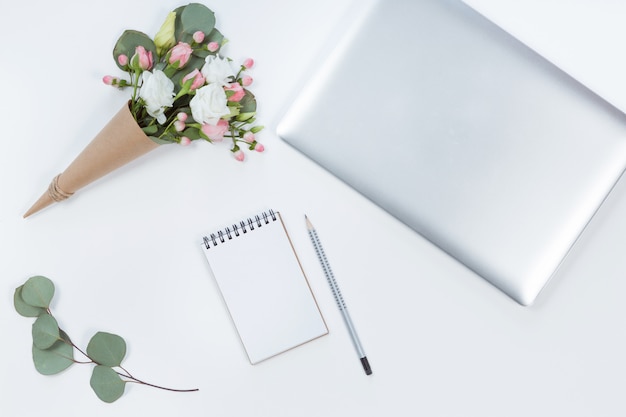 Bovenaanzicht van thuiskantoor desktop van laptop, bloemen op kegel en laptop. Plat leggen van werkruimte met kopie ruimte