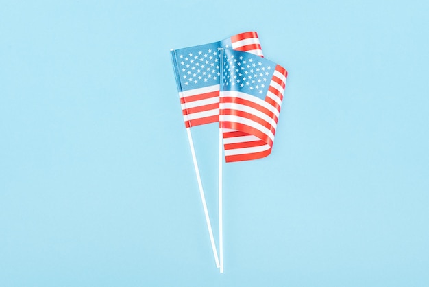 Bovenaanzicht van twee Amerikaanse vlaggen op stokjes op blauwe achtergrond