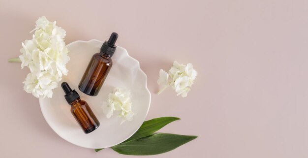 Bovenaanzicht van twee cosmetische flessen met een druppelaar met een natuurlijk product voor extra zelfzorg op een witte abstracte plaatbanner